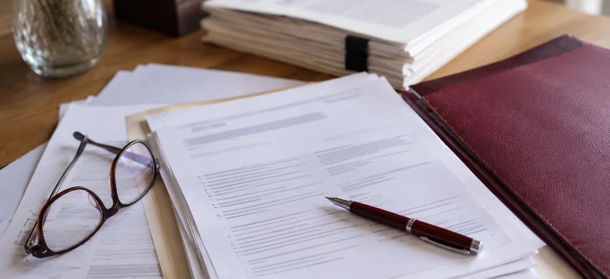 Documentos legales sobre la mesa para decidir entre aceptar, renunciar o pedir el beneficio de inventario en una herencia con deudas.